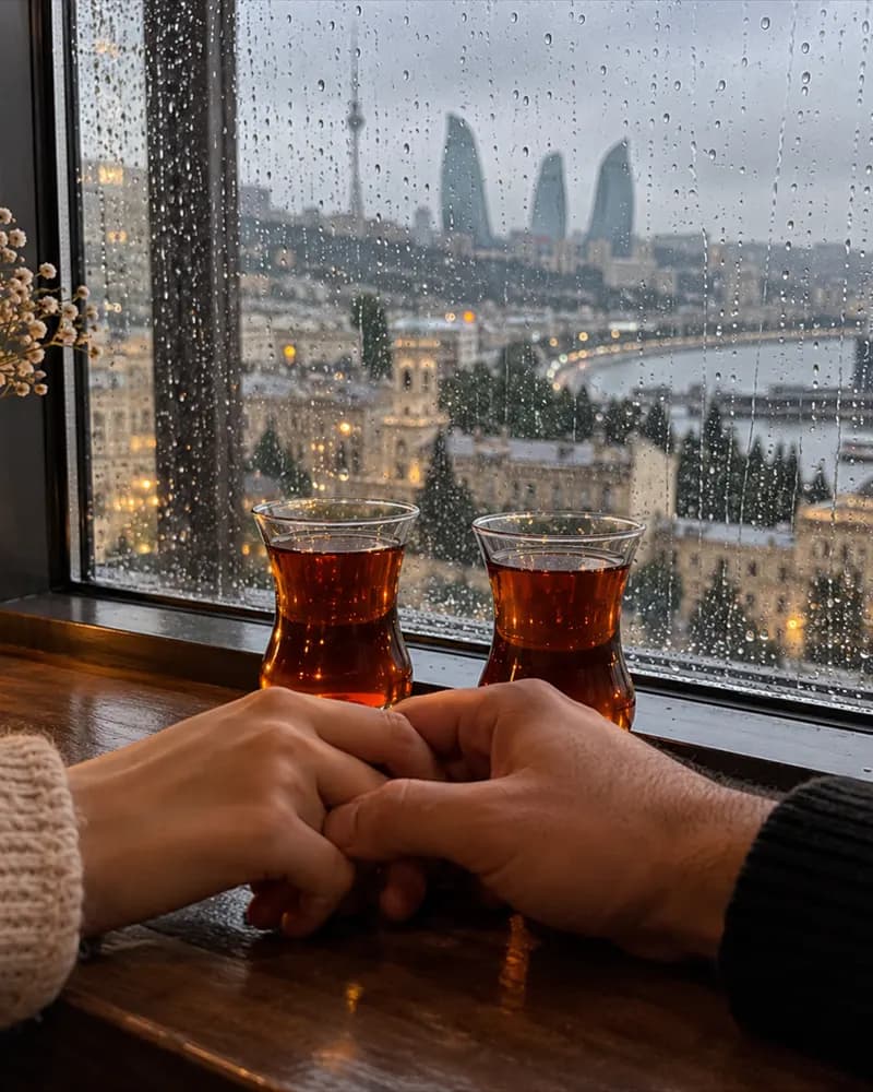 Yağışlı pəncərə qarşısında iki armudu stəkan çay və bir-birinə toxunan iki əl